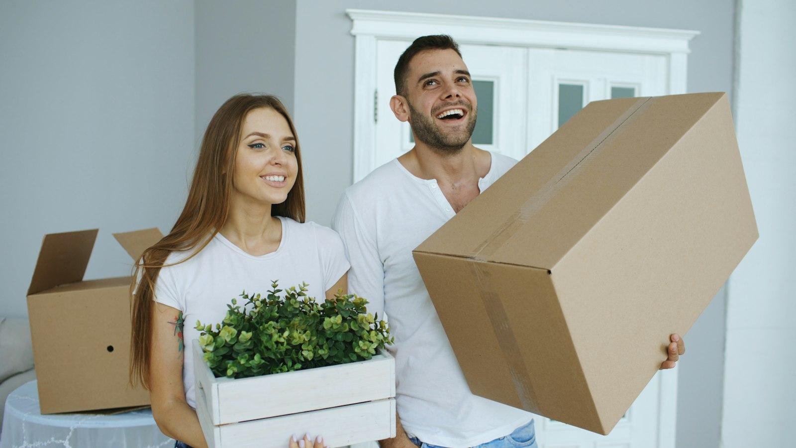 Deux personnes avec des cartons et une plante le jour d’un emménagement